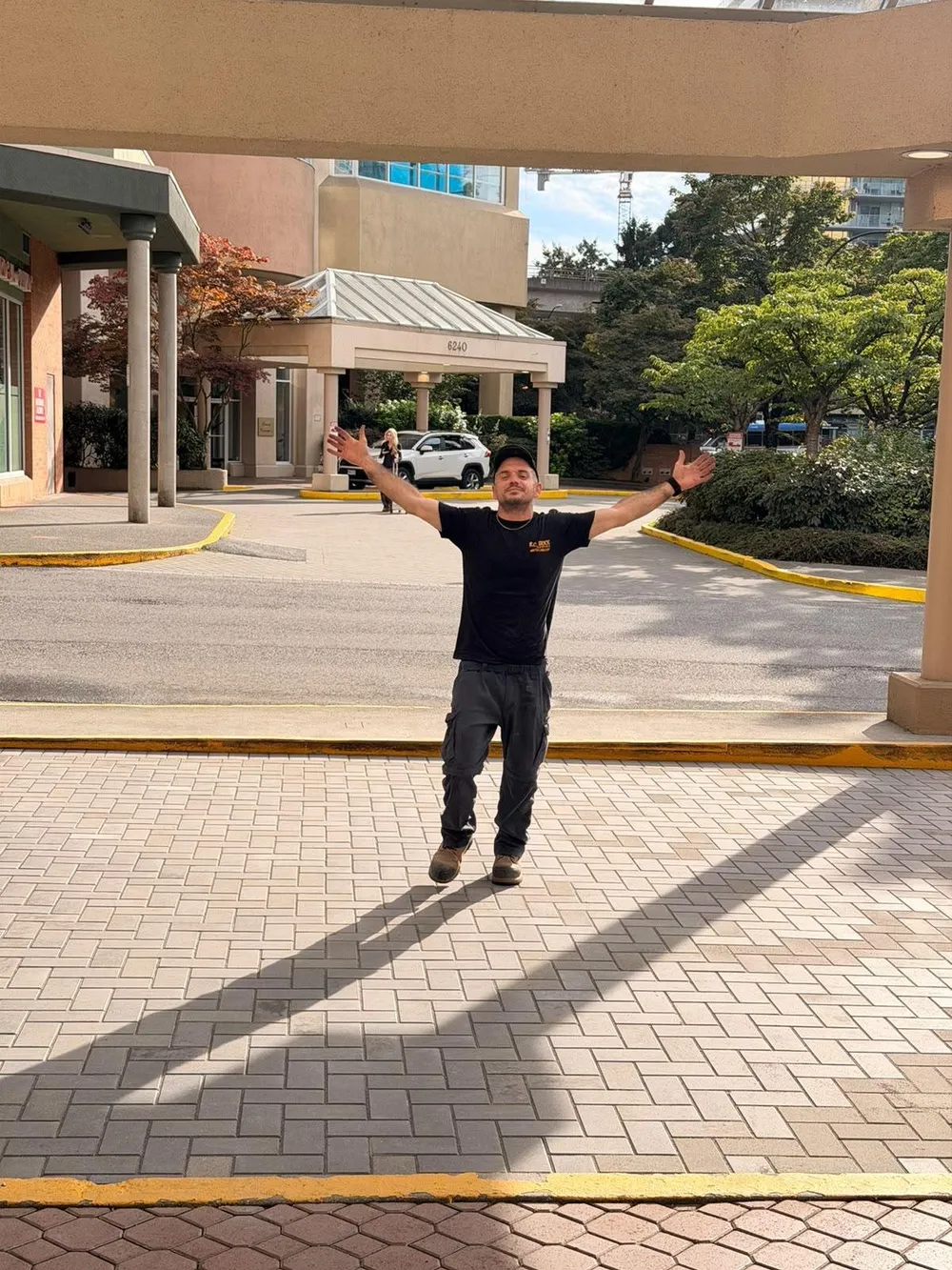 Loris standing arms wide on a newly laid herringbone paver forecourt