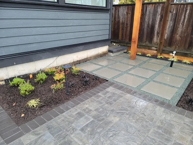 Square pavers set in gravel beside new planting and lighting fixtures
