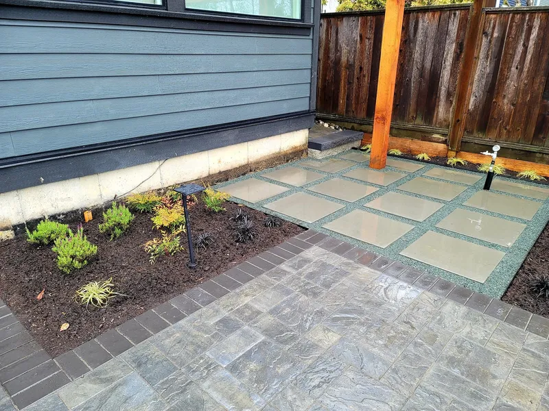 Planted garden bed with drip irrigation beside a paver patio