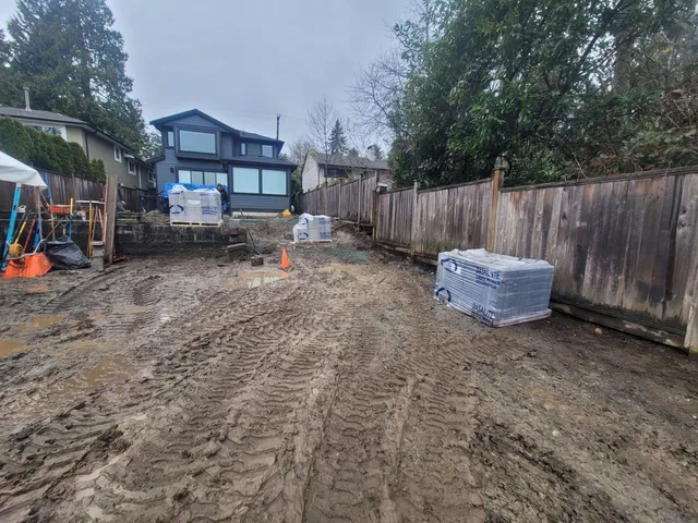 The same backyard before: bare mud after excavation, with materials staged