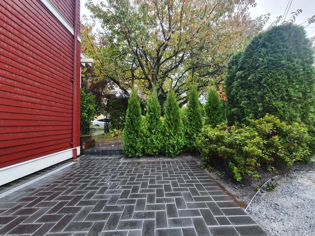 Herringbone paver driveway beside a red house