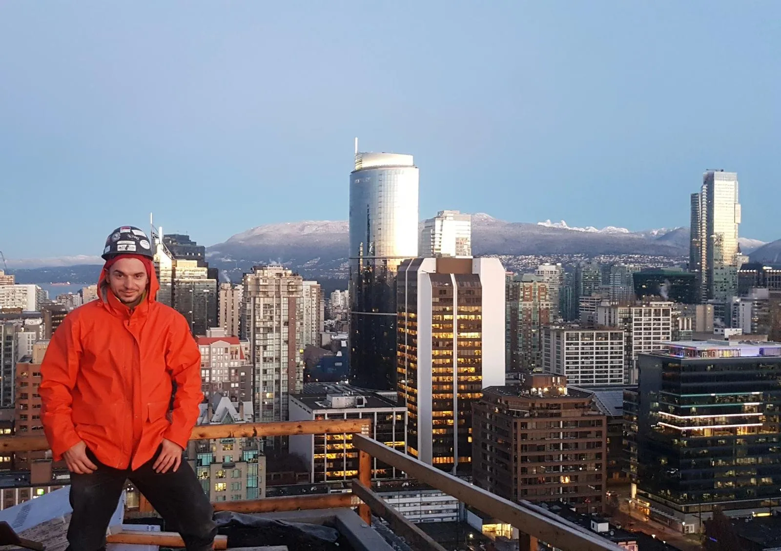Loris on a downtown rooftop with the Vancouver skyline and North Shore mountains behind him